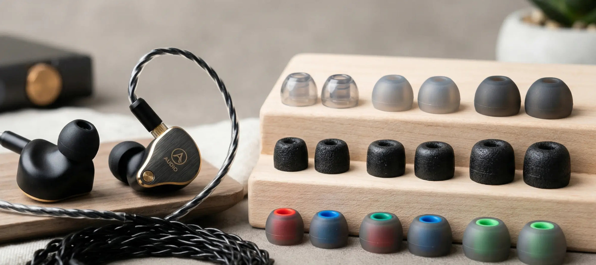High-quality in-ear monitor (IEM) earbuds displayed with an assortment of silicone and memory foam ear tips arranged neatly on a wooden stand.