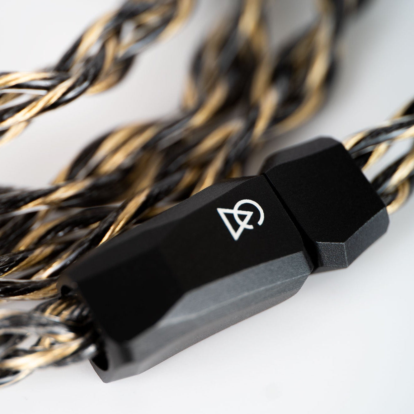 Coiled black and gold audio cable with a branded connector on a light gray background